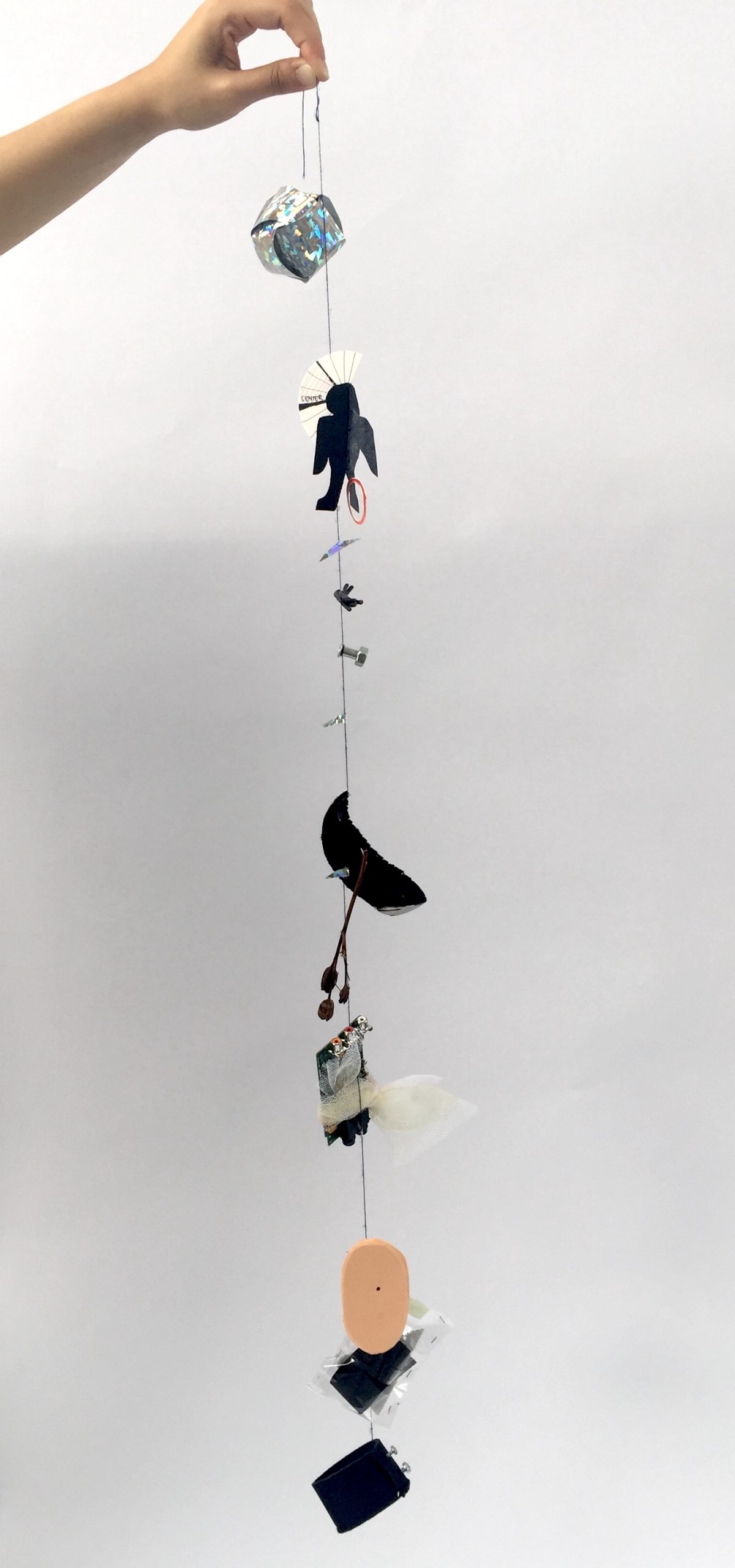 Photo of hand dangling a long string with decorative objects